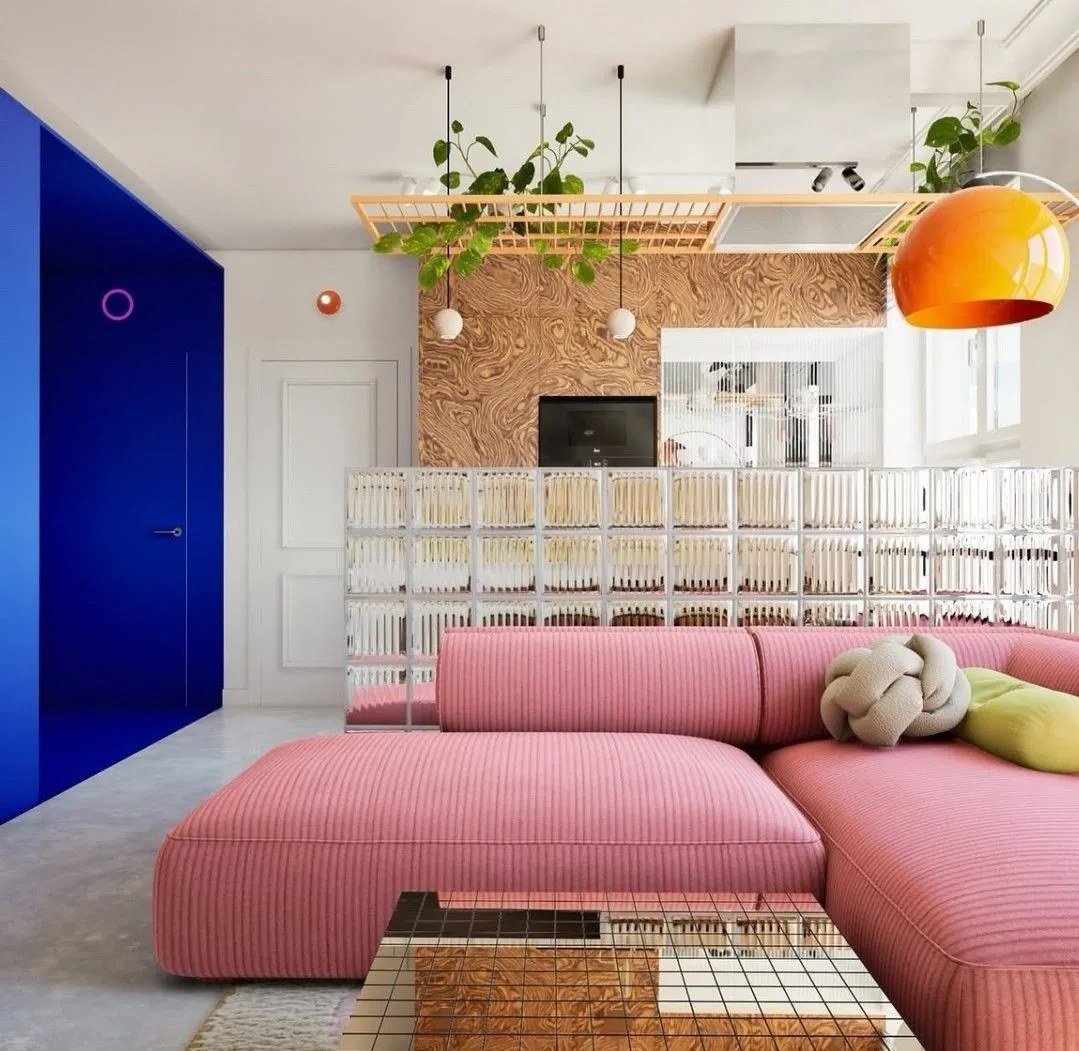 Salón colorido con sofá rosa, pared azul y piezas decorativas
